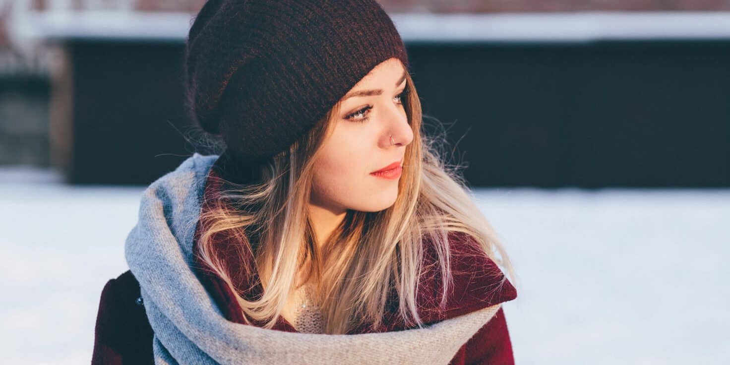 A woman in a winter hat and scarf, looking cozy and warm.