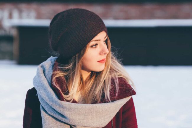 A woman in a winter hat and scarf, looking cozy and warm.