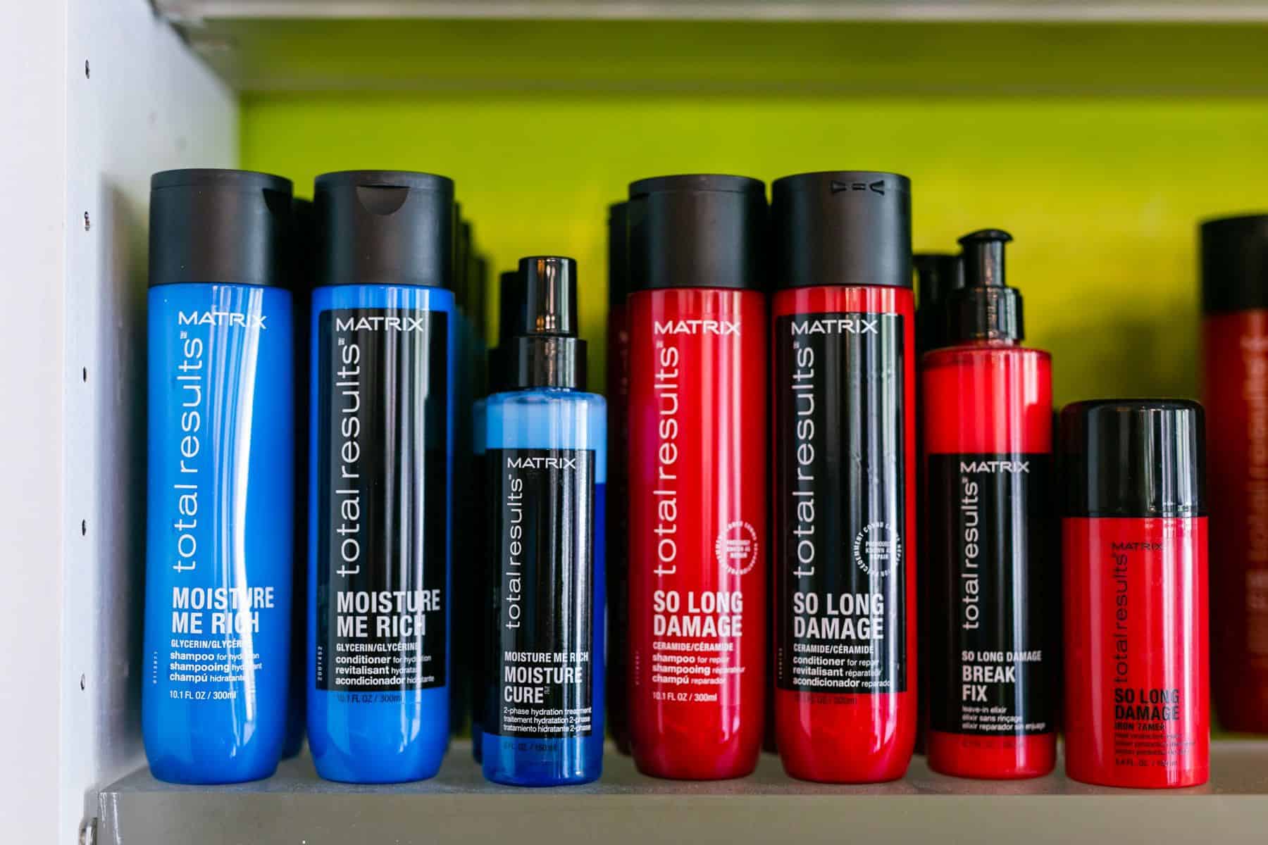 Assorted hair products neatly arranged on a shelf, including shampoos, conditioners, and styling products.