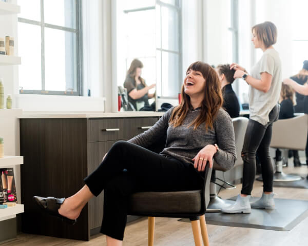 A woman sitting in a salon chair, getting her hair styled by a professional.