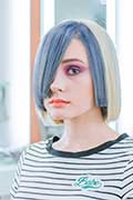 A woman with a blue hair cut confidently gazes at the camera, exuding a sense of style and individuality.