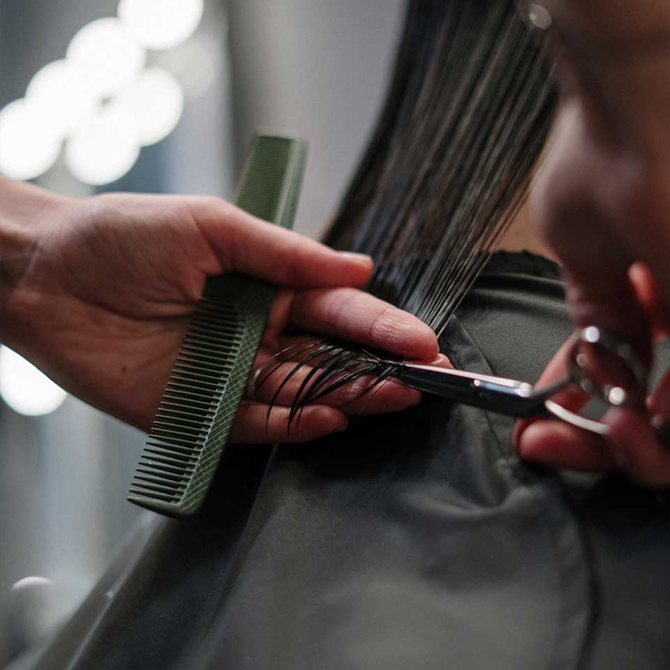 A hairstylist using a comb to cut a woman's hair, creating a stylish and precise haircut.