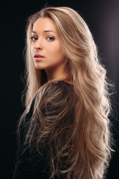 A stunning young woman with blonde balayage rubio flowing hair, radiating beauty and grace.